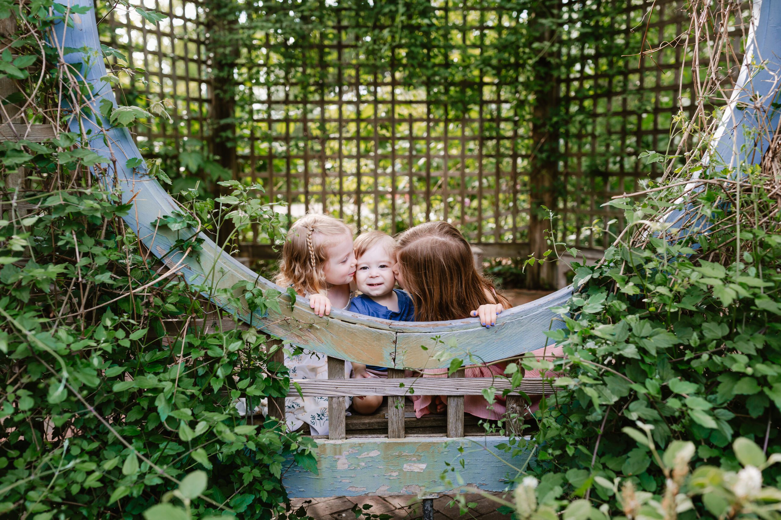 Spring mini sessions. Westerville Ohio family photographer. Children showing each other love, surrounded by green ivy.
