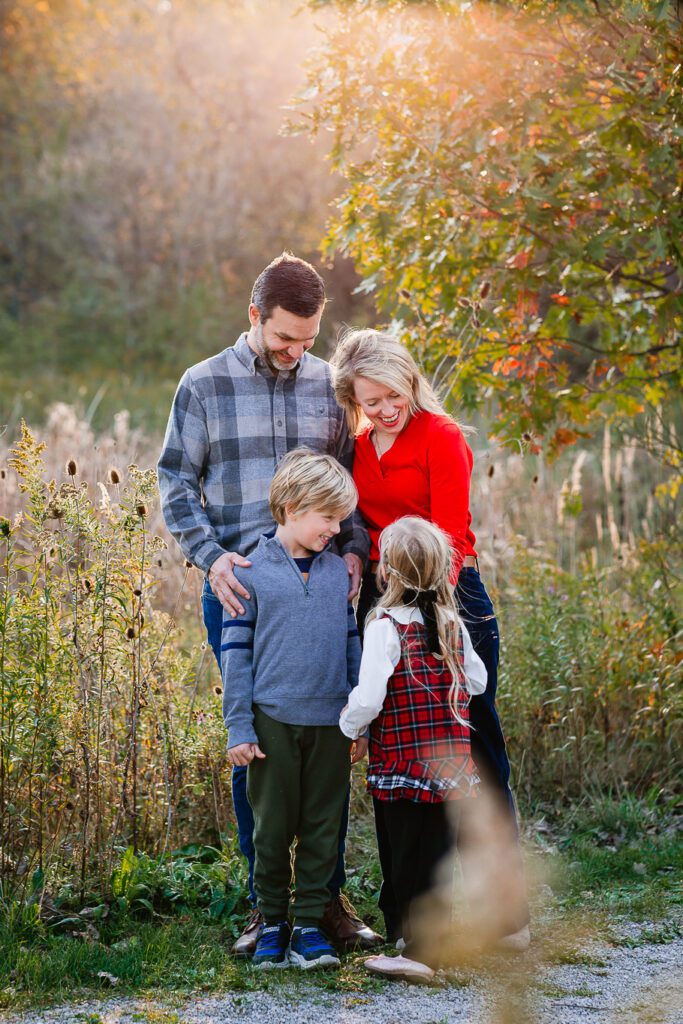 Family smiling at each other in a fall forest setting. Christy Rice Photography fall mini session