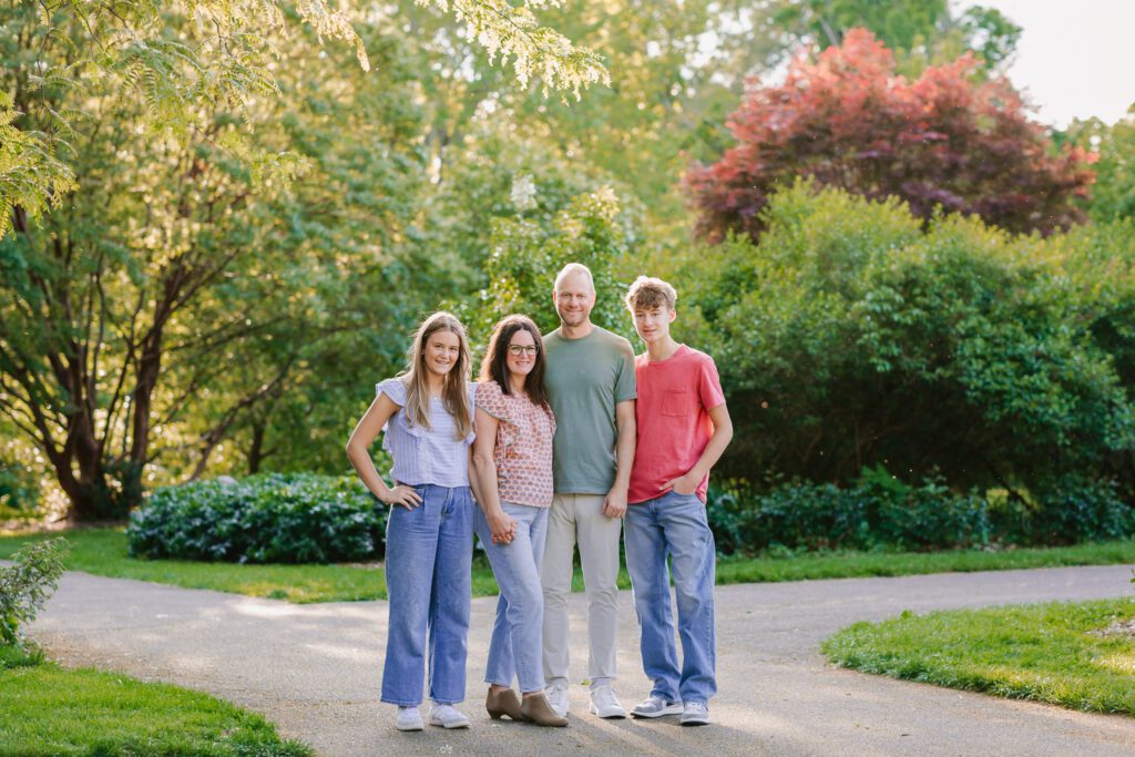 A family of four smiles at the camera during their family photography session with Christy Rice Photography at Columbus Park of Roses in Columbus, Ohio.